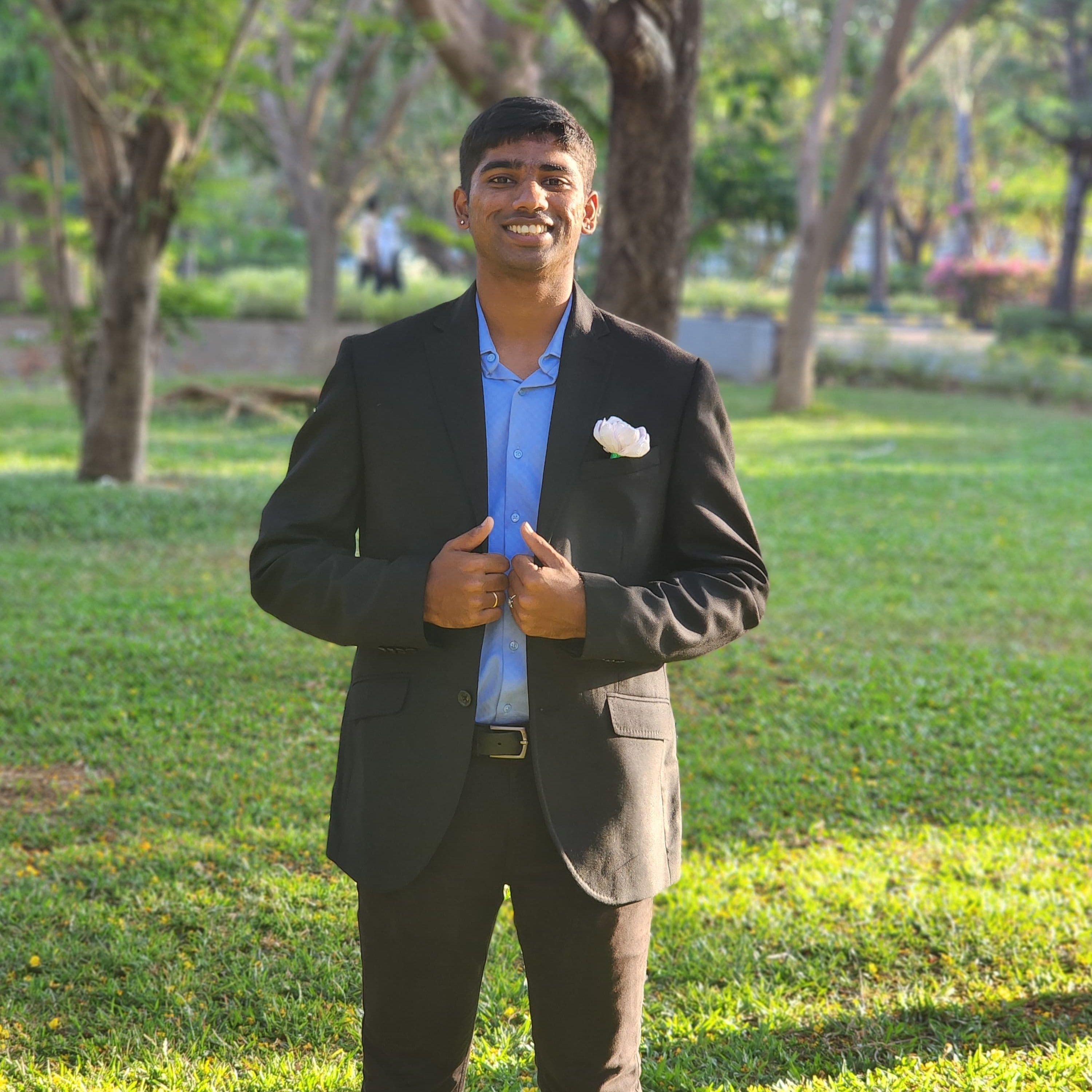 Raghav Nallaperumal in a black suit standing in a park